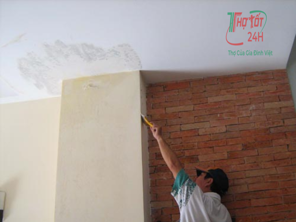 Thợ kiểm tra nguyên nhân khiến trần nhà bị thấm nước và cạo lớp vữa bong tróc