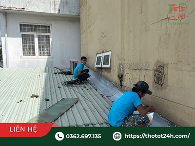 Thợ chống thấm đang thi công gia cố tấm che khe tiếp giáp nhà bị dột nước mưa trên mái nhà phố.