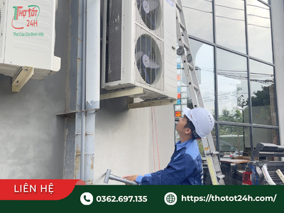Thợ kỹ thuật đội mũ bảo hộ kiểm tra dàn nóng ngoài cao khi cung cấp dịch vụ sửa máy lạnh thuận an