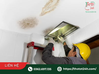 Thợ kiểm tra nguyên nhân trần nhà bị dột qua lỗ thăm trần thạch cao khi trời mưa.